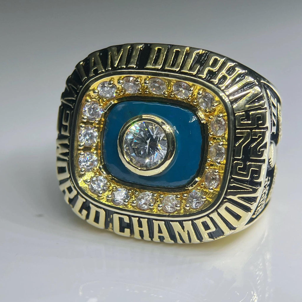 Gold and blue championship ring with engraved text on a gray background