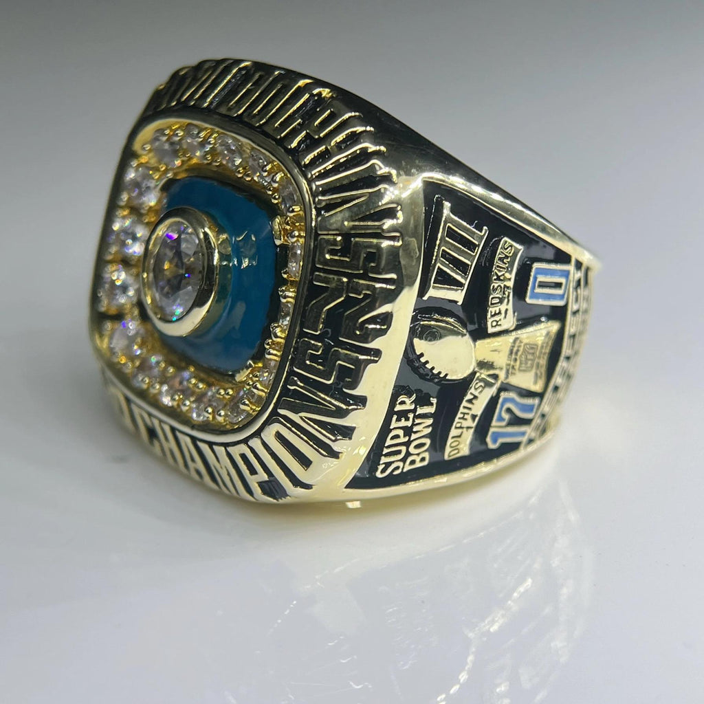 Gold championship ring with blue and black details on a white background