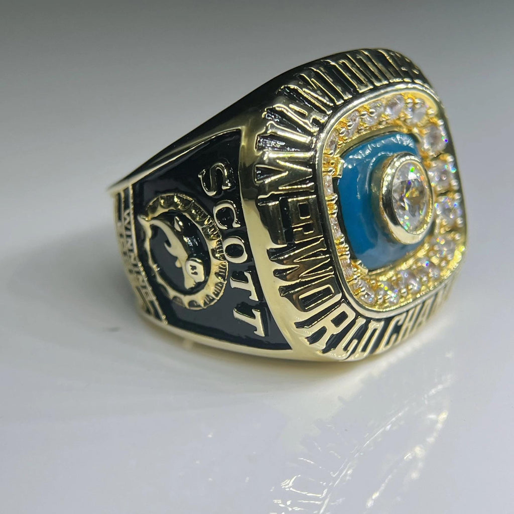 Gold championship ring with blue and black accents on a white background