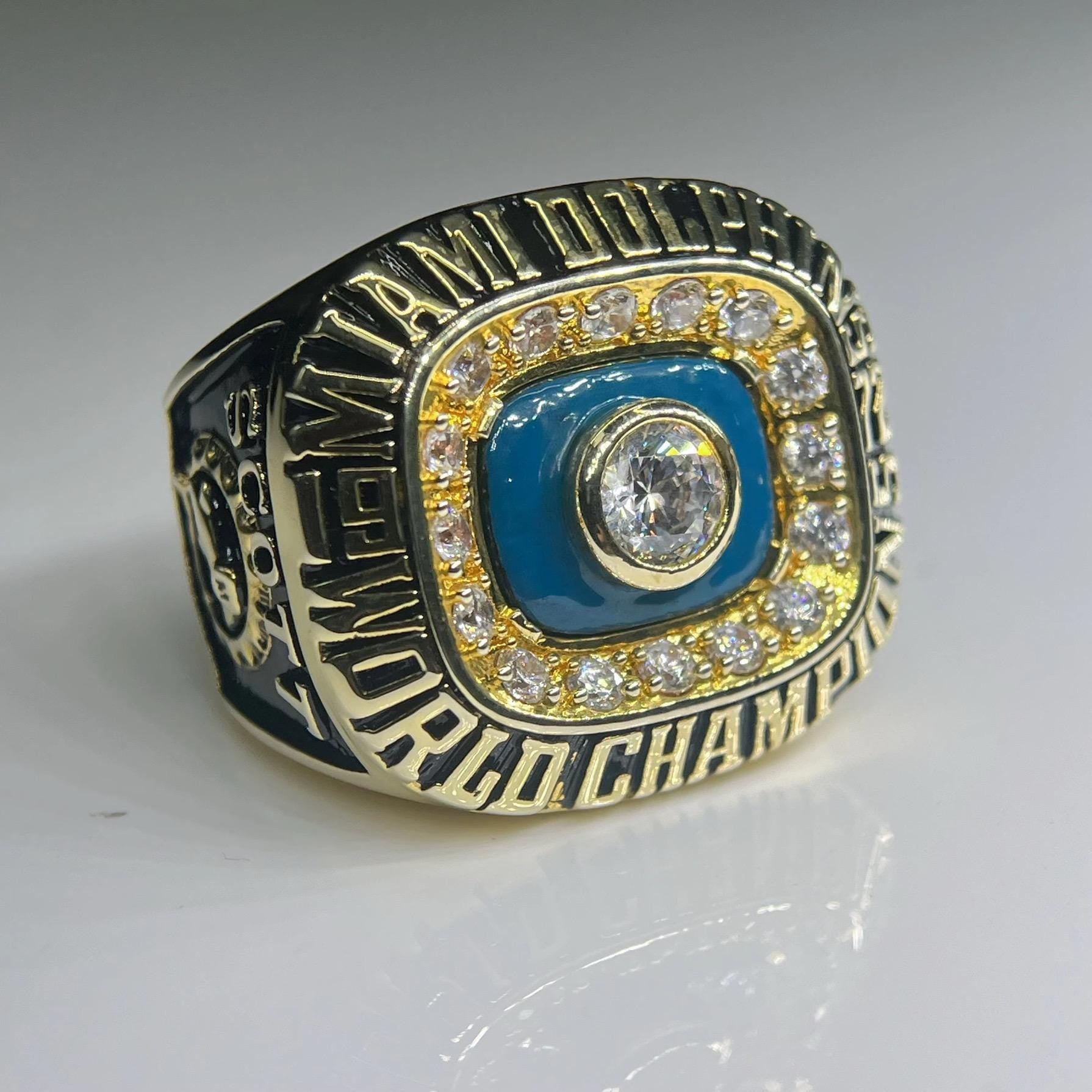 Gold and blue championship ring with diamond accents on a gray background