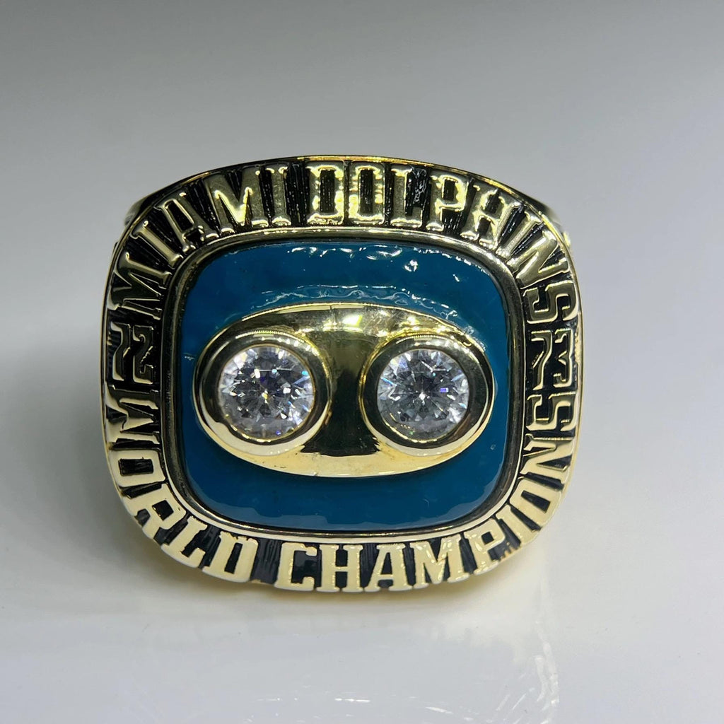 Gold and blue championship ring with two diamonds on a gray background