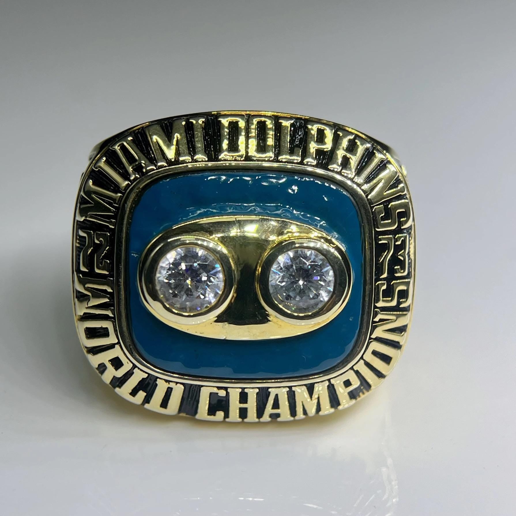 Gold and blue championship ring with two diamonds on a gray background