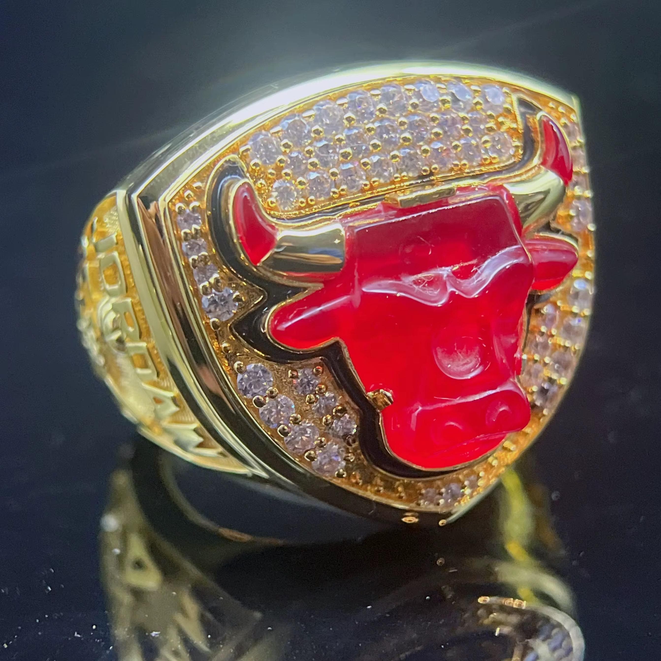 Gold ring with red bull logo on a reflective surface