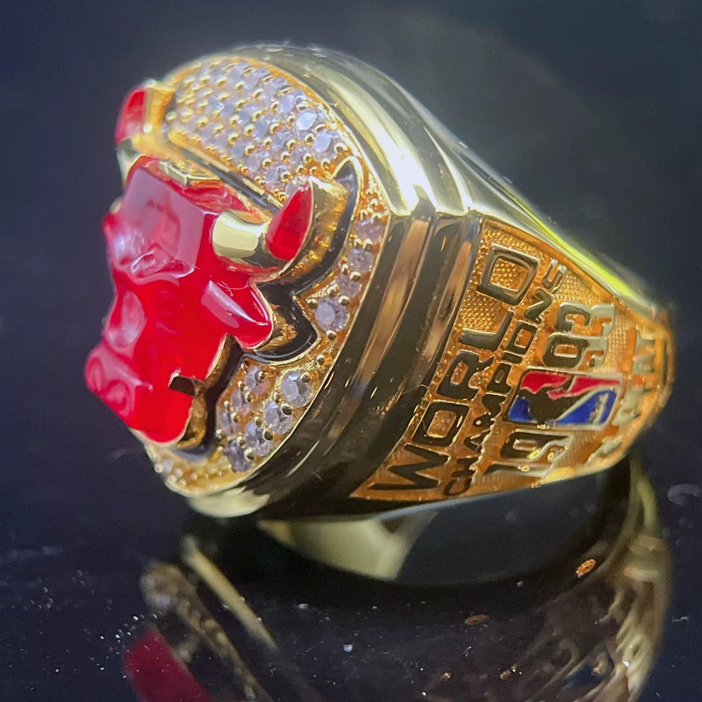 Gold championship ring with red bull emblem on a dark background