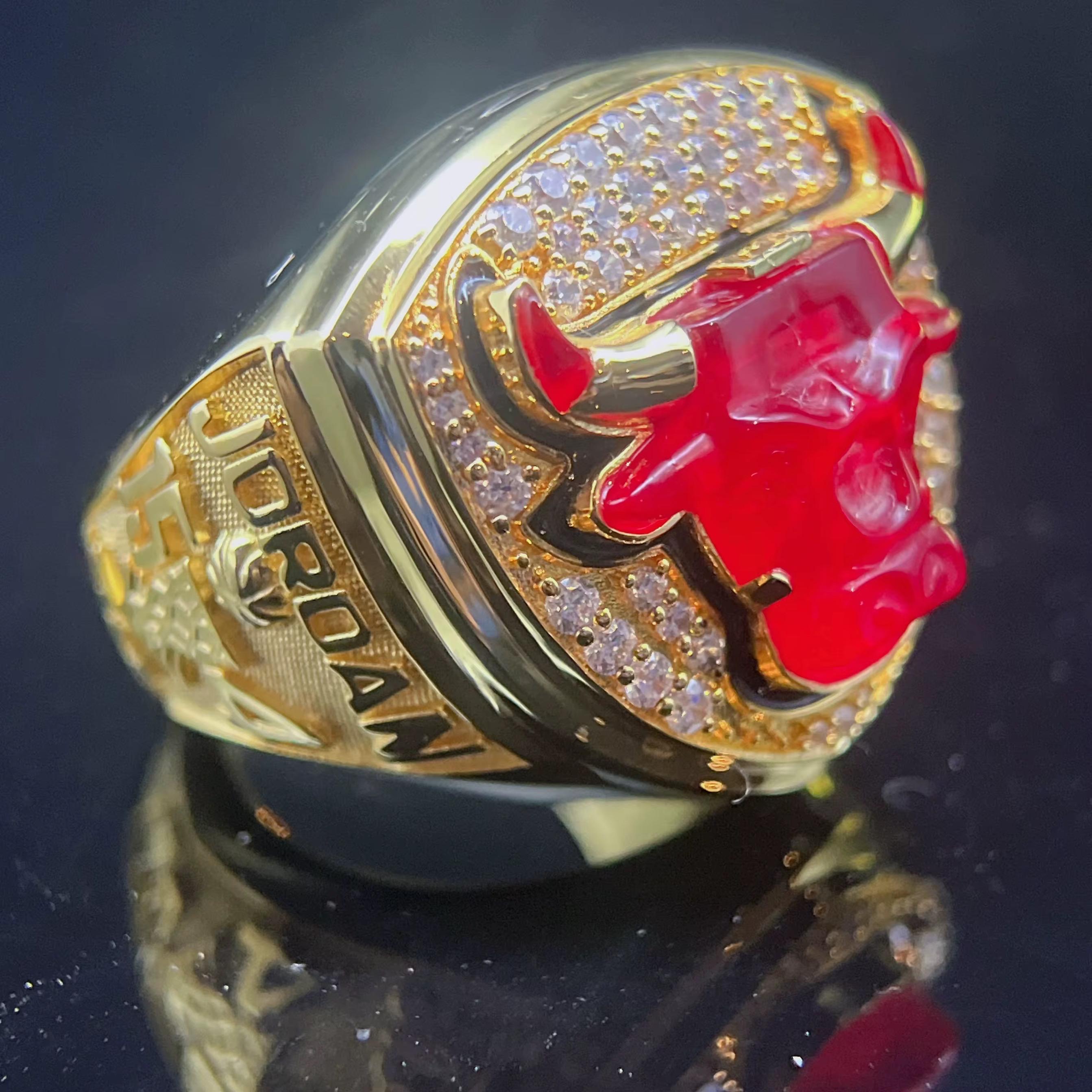 Gold ring with red bull emblem and 'Jordan' branding on a dark background
