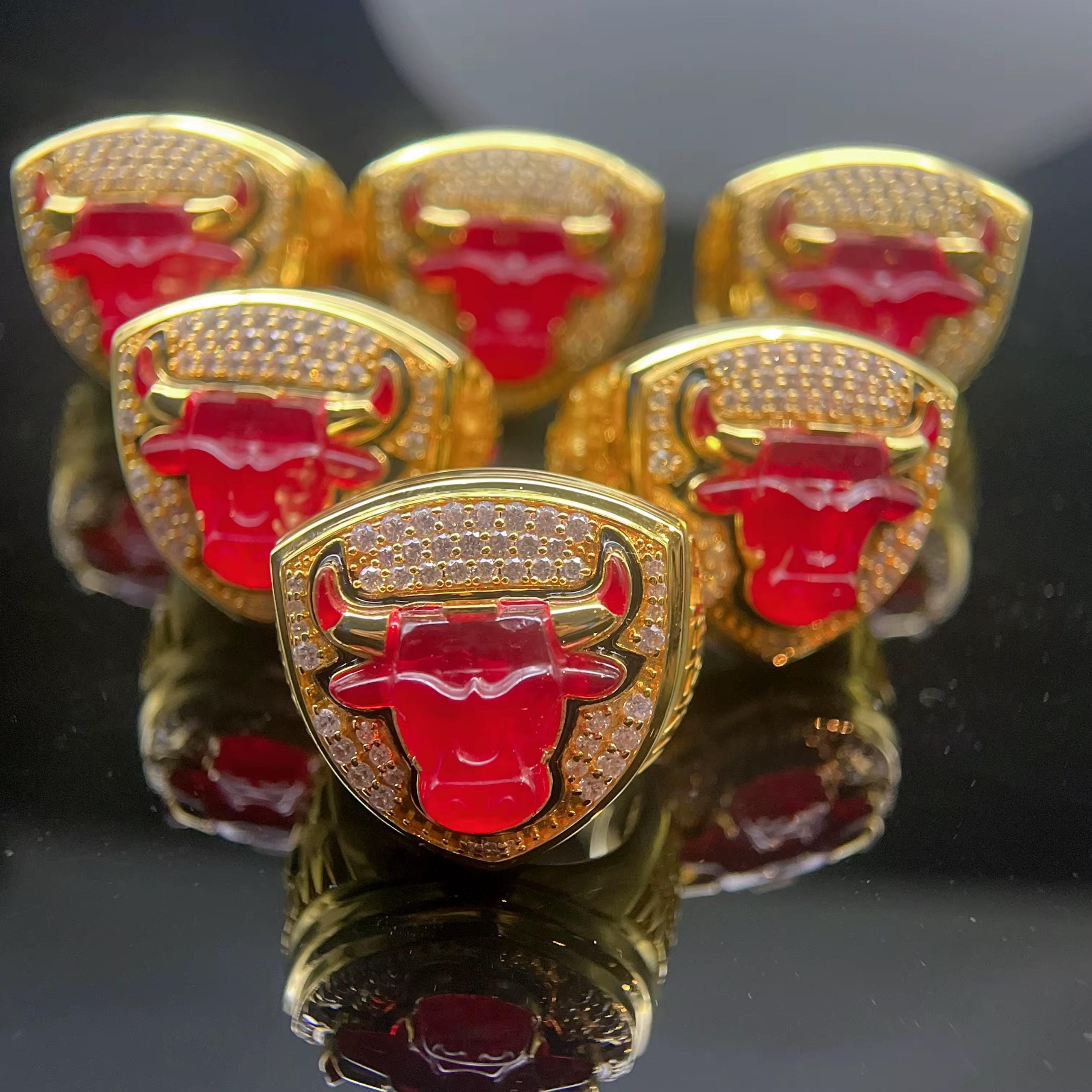 Gold and red emblems with a bull design on a reflective black surface