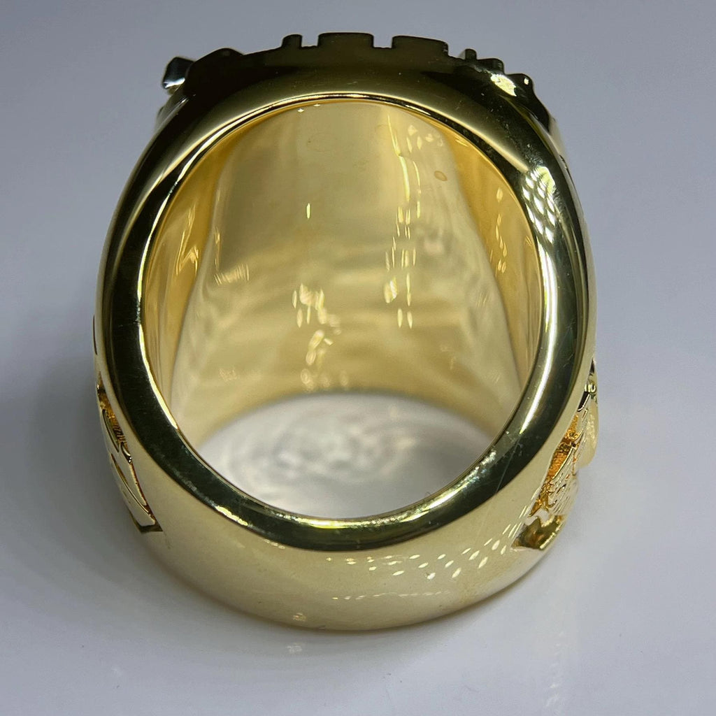 Gold ring with intricate design on a gray background