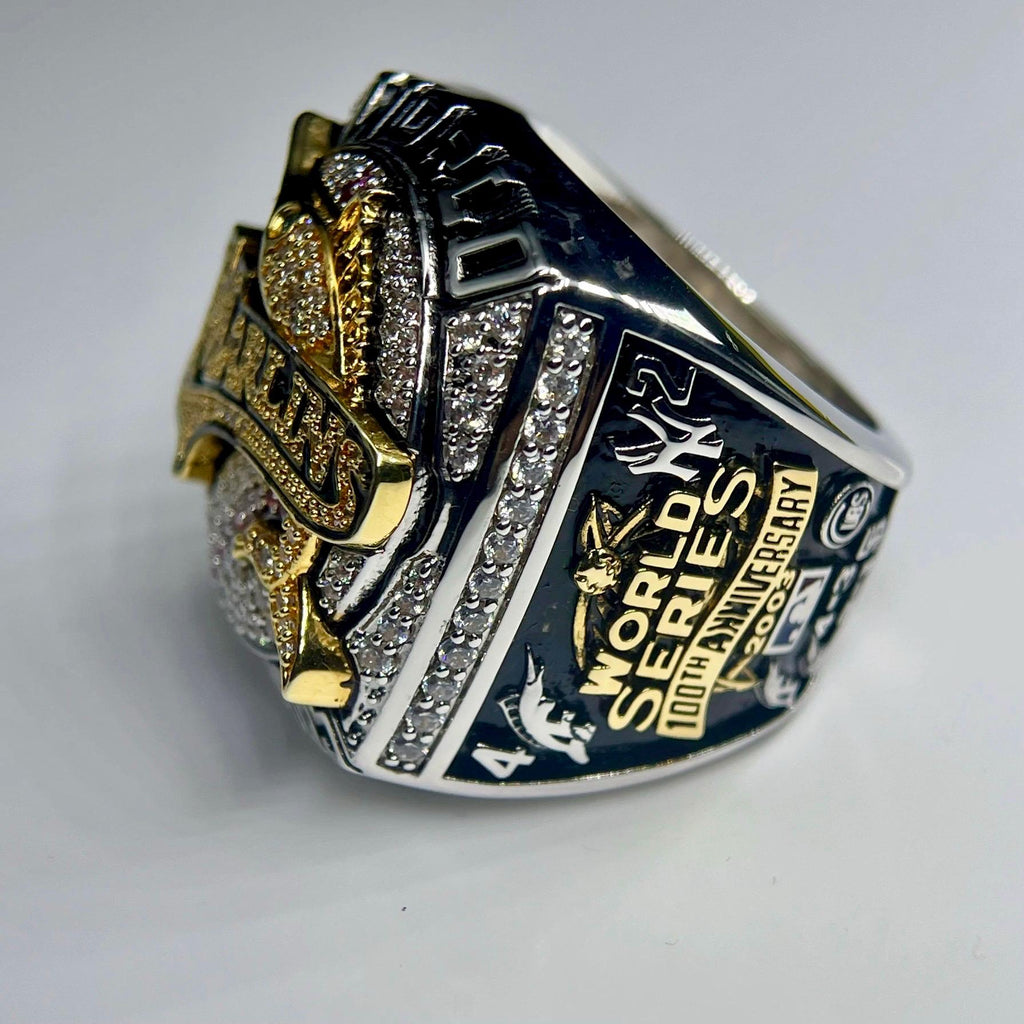 Close-up of a World Series championship ring with gold and silver accents on a light gray background.