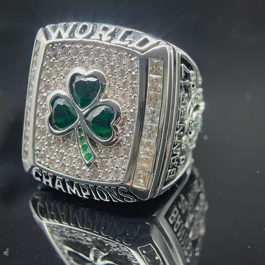 Silver championship ring with a green shamrock on a reflective surface
