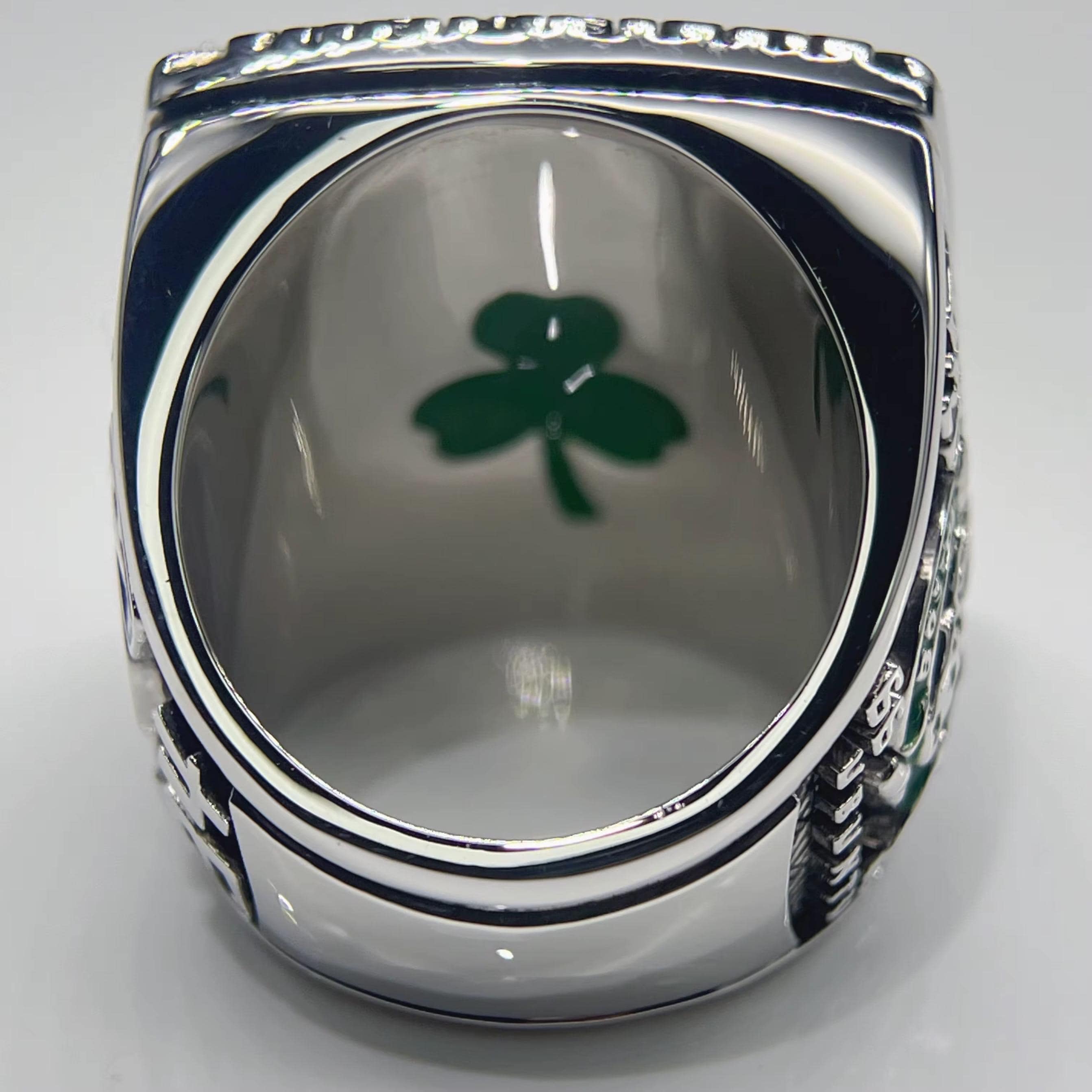 Silver ring with a green clover design on a gray background