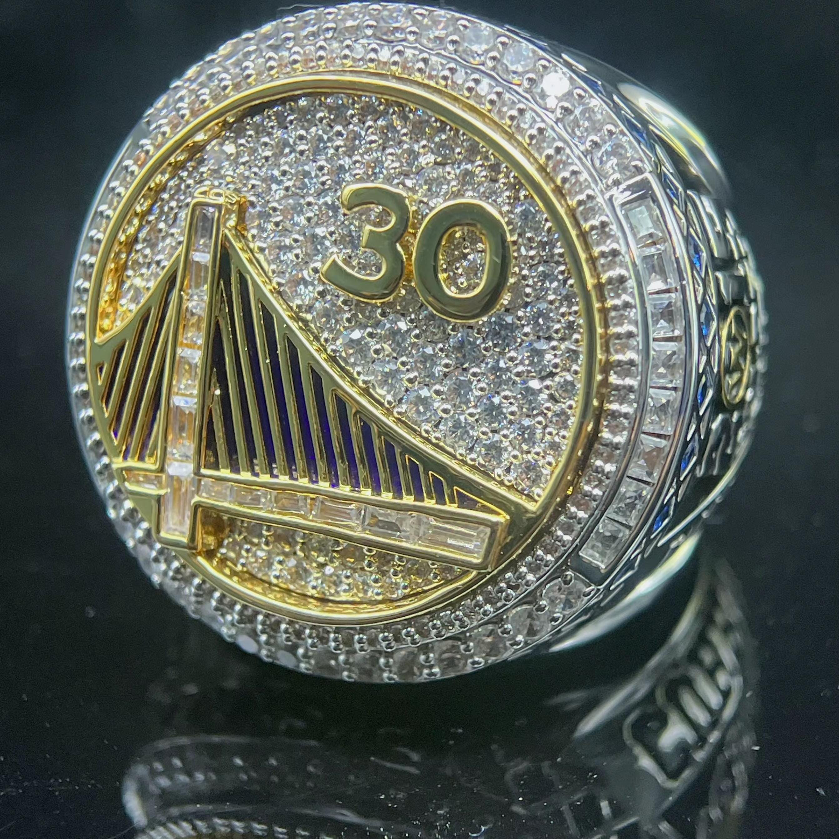 Close-up of a championship ring with '30' and a logo on a dark background