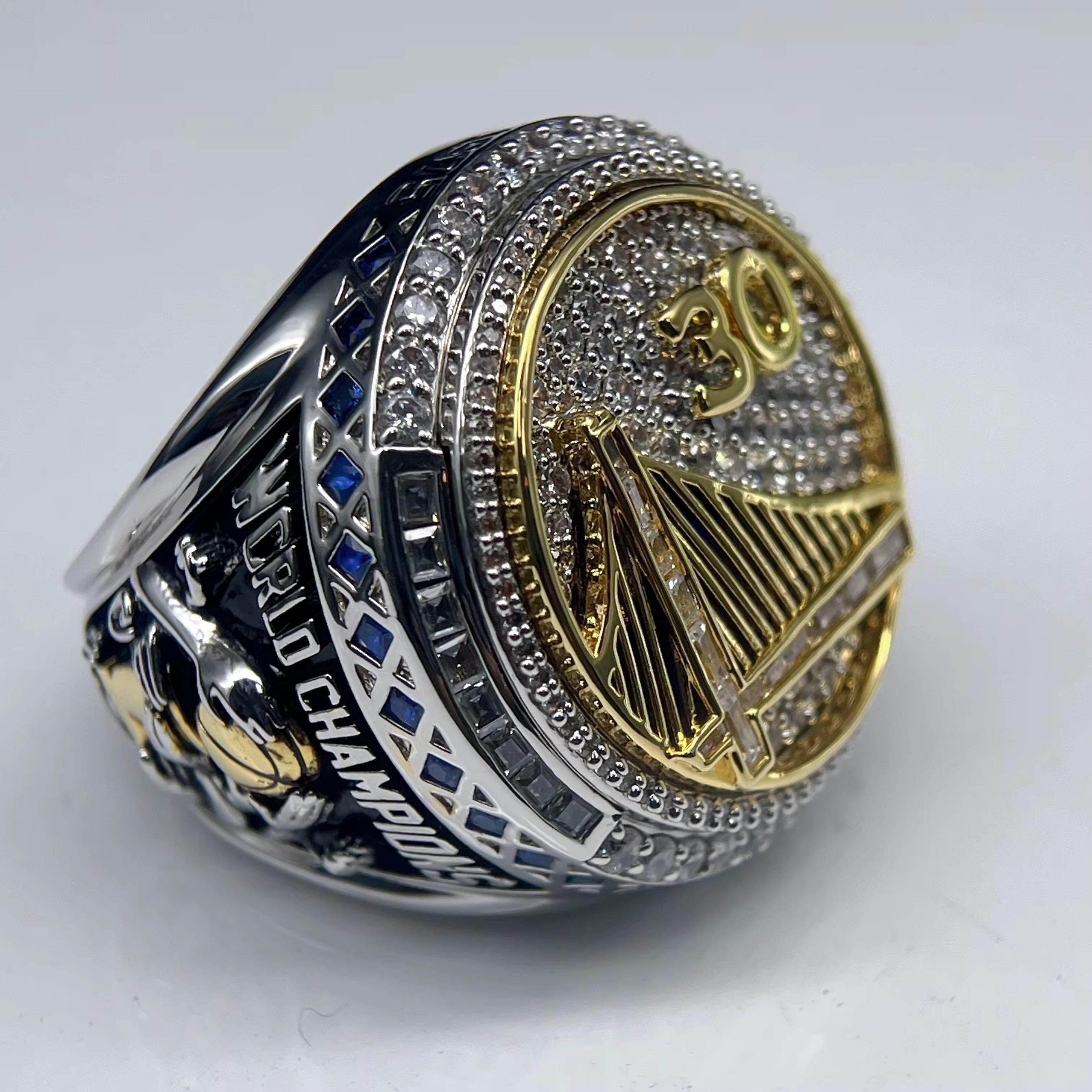 Silver and gold championship ring with 'World Champions' text on a white background