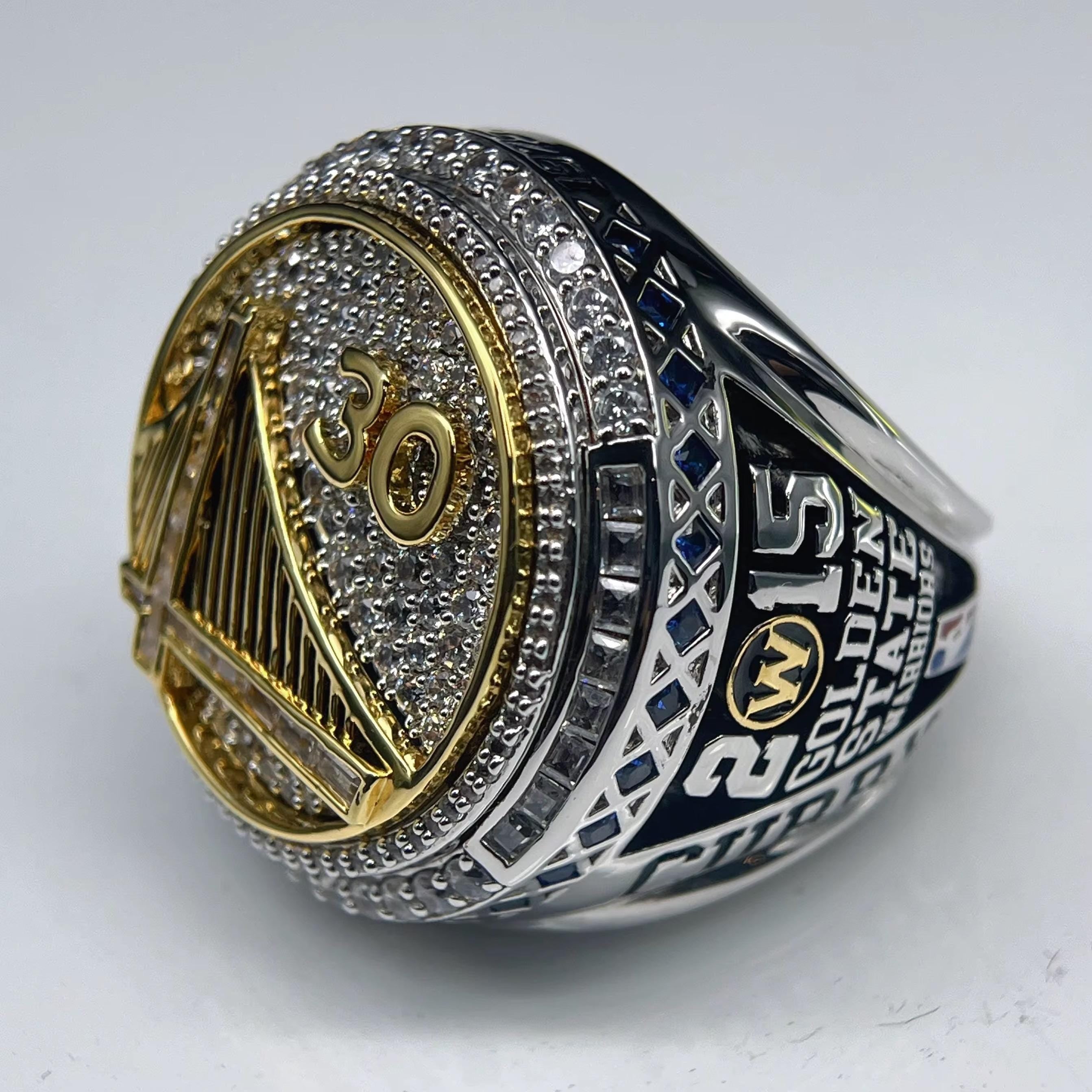 Close-up of a championship ring with '2015' and 'Golden State' text on a white background