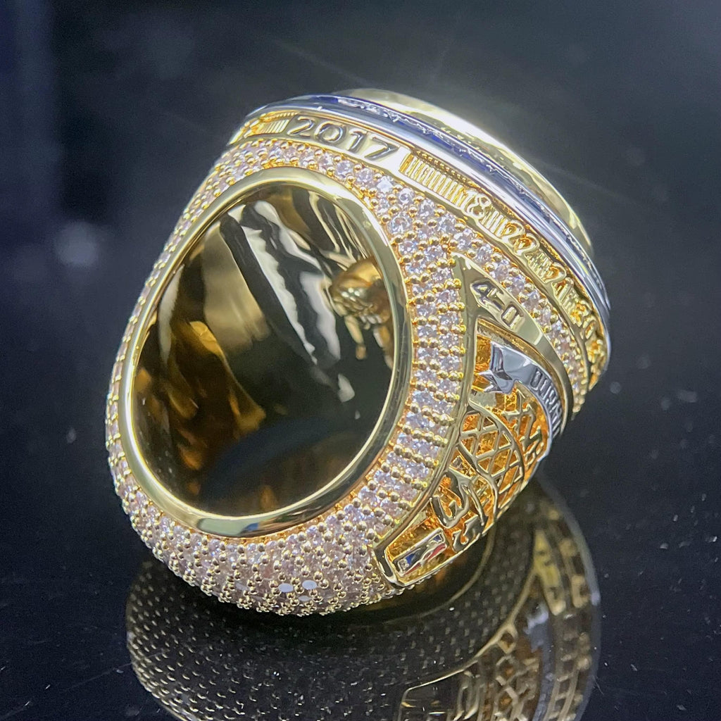 Gold and silver ring with intricate design on a reflective surface