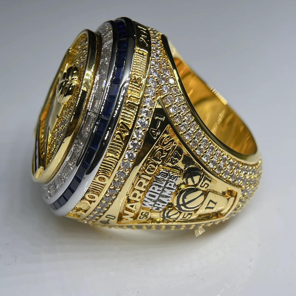 Gold championship ring with engraved text on a gray background
