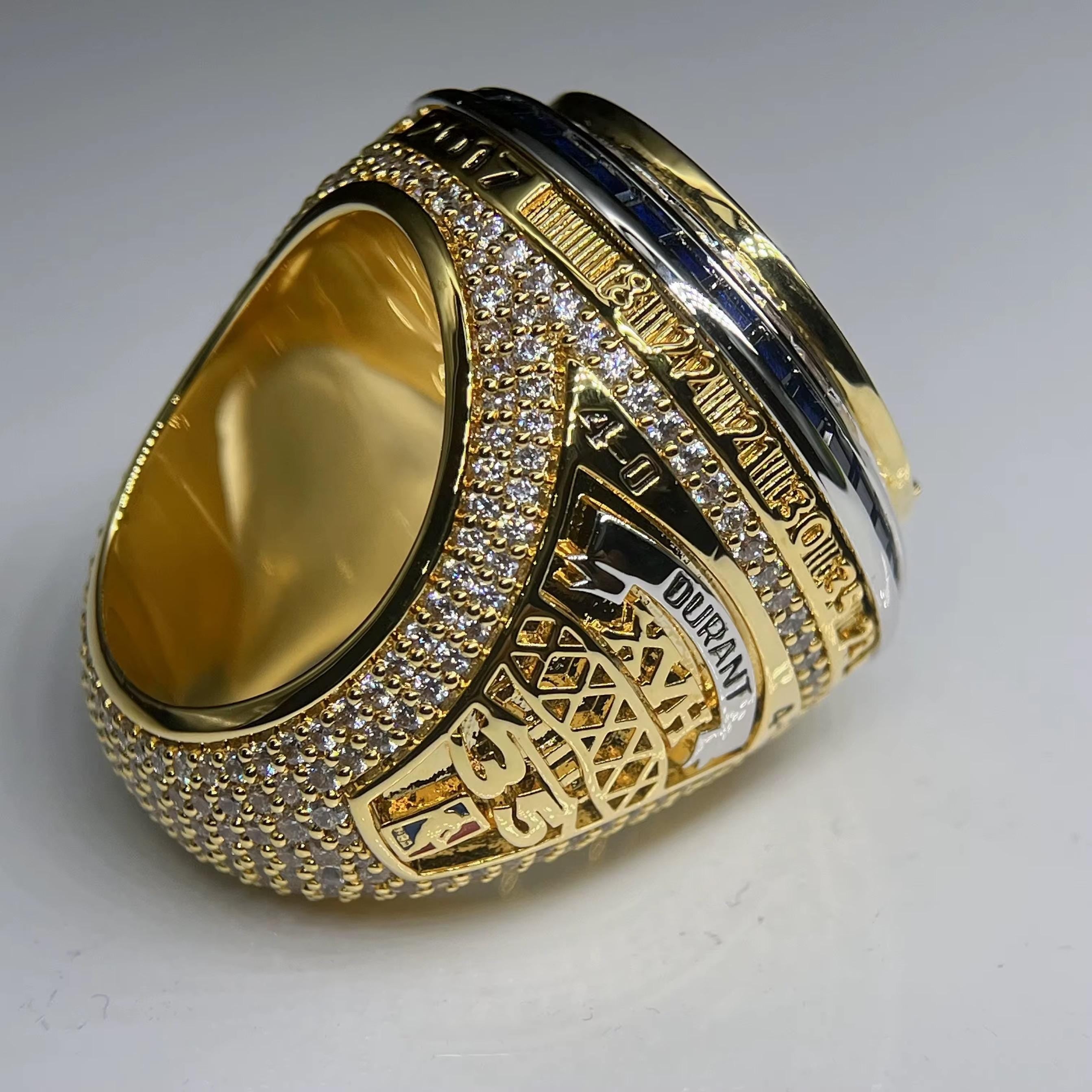 Gold ring with intricate design and text on a light gray background