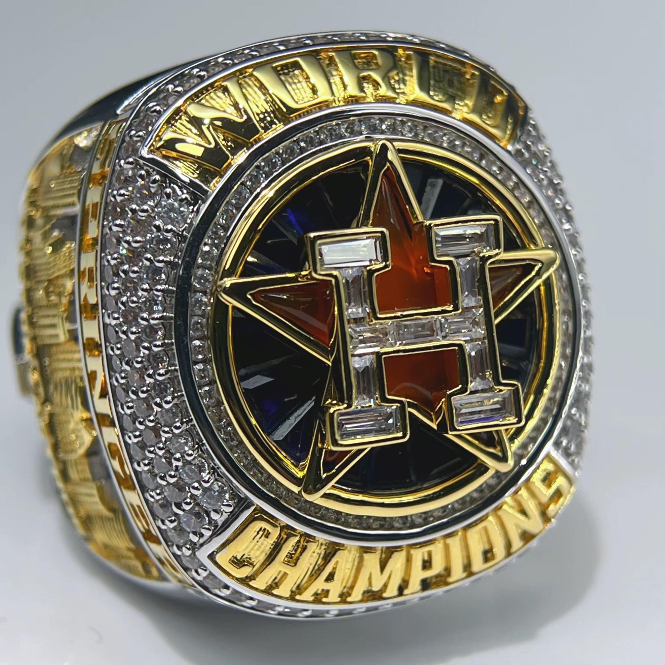 Gold and silver championship ring with a prominent logo on a gray background