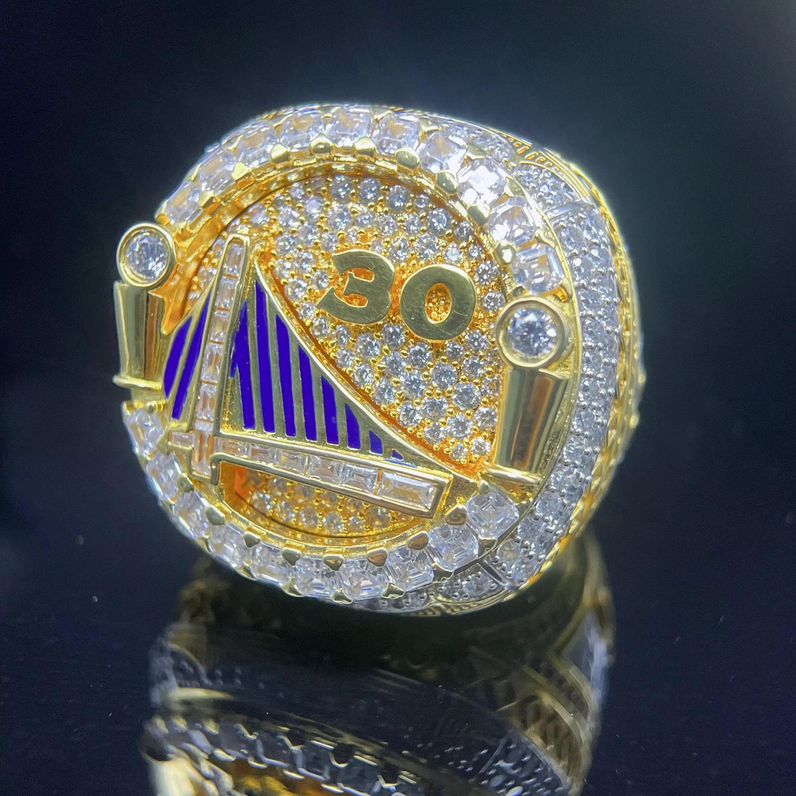 Gold championship ring with '30' and emblem on a dark background