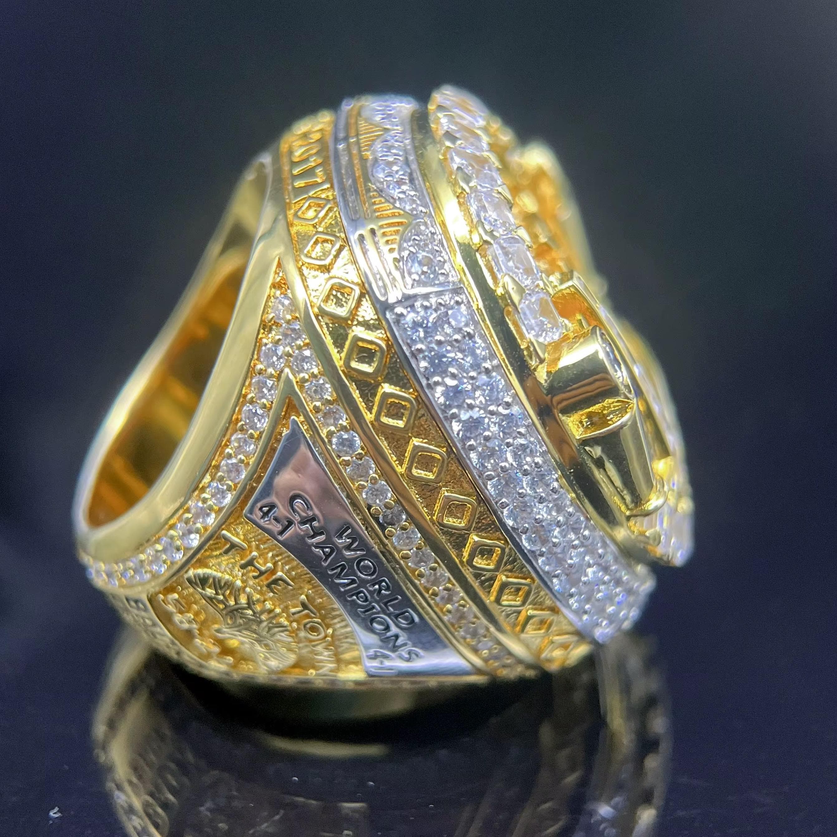 Gold and silver ring with intricate designs on a dark background