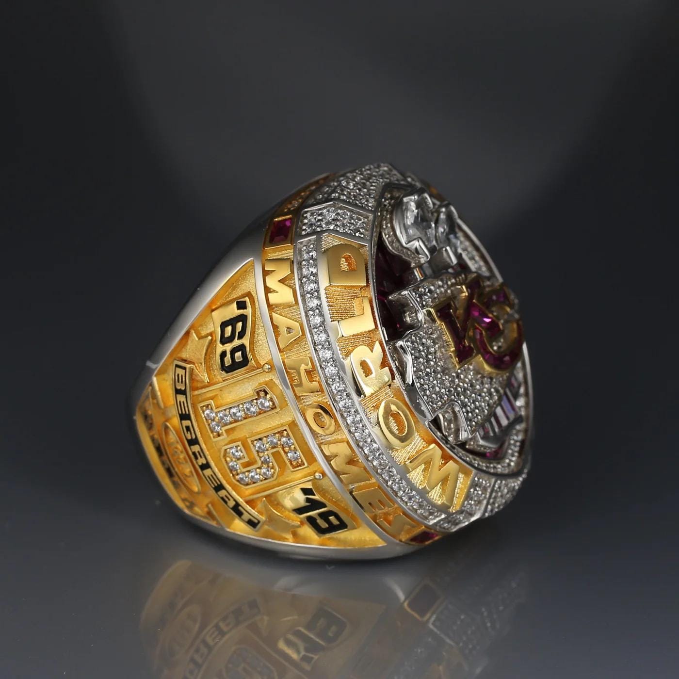 Gold and silver ring with engraved text on a dark background