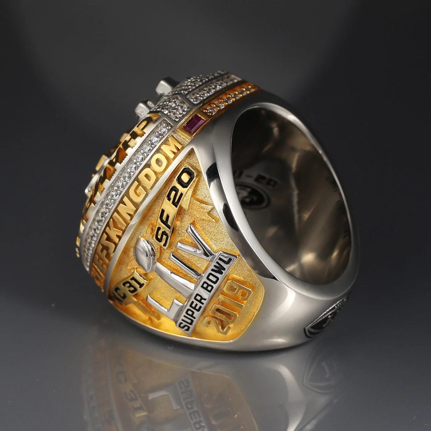 Silver and gold championship ring with text on a dark background
