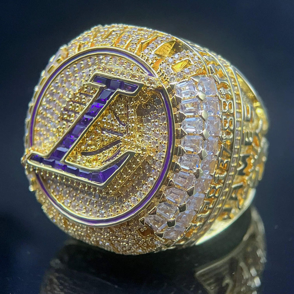 Gold ring with a prominent 'L' symbol on a dark background