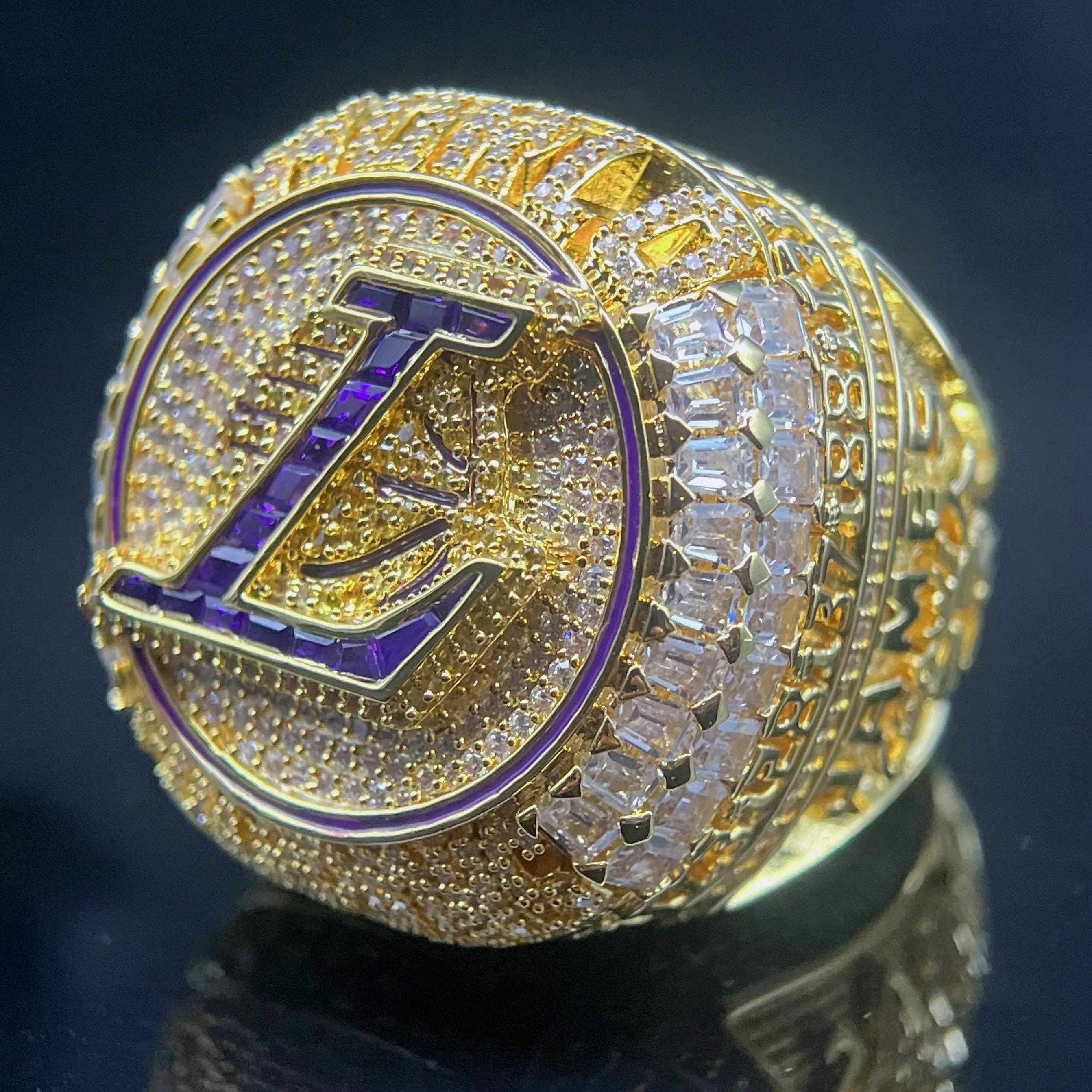 Gold ring with a prominent 'L' symbol on a dark background