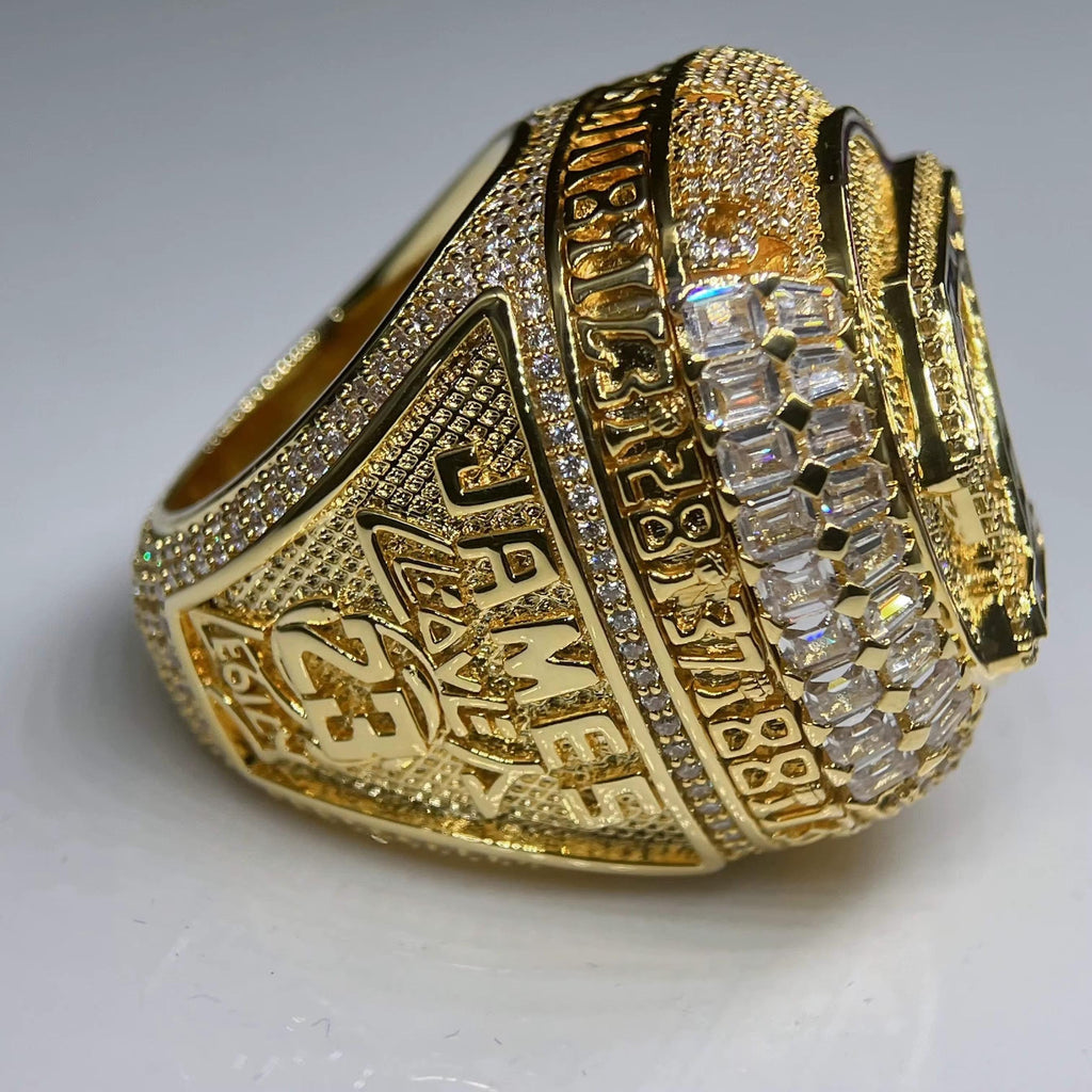 Gold championship ring with engraved text and diamond accents on a white background