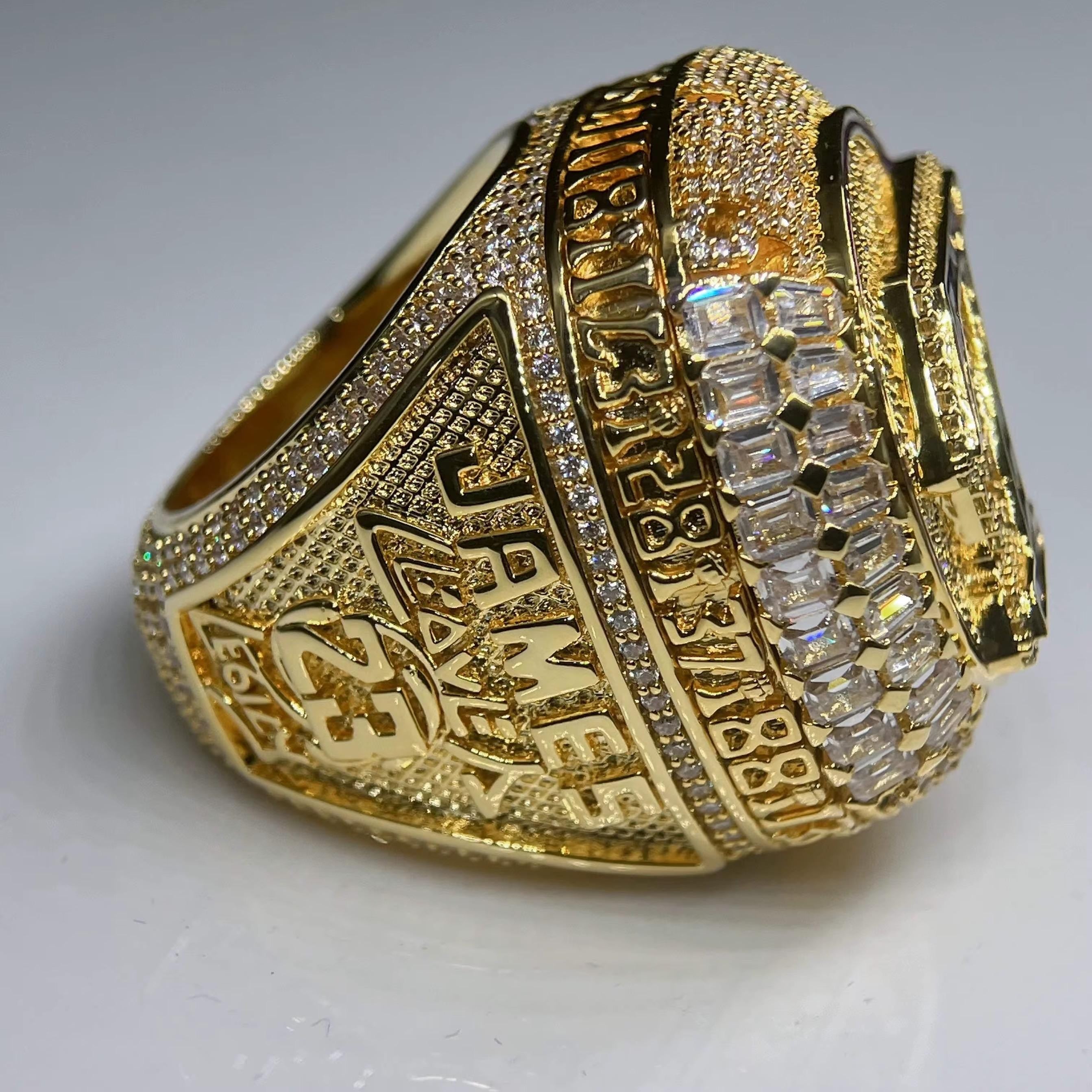 Gold championship ring with engraved text and diamond accents on a white background