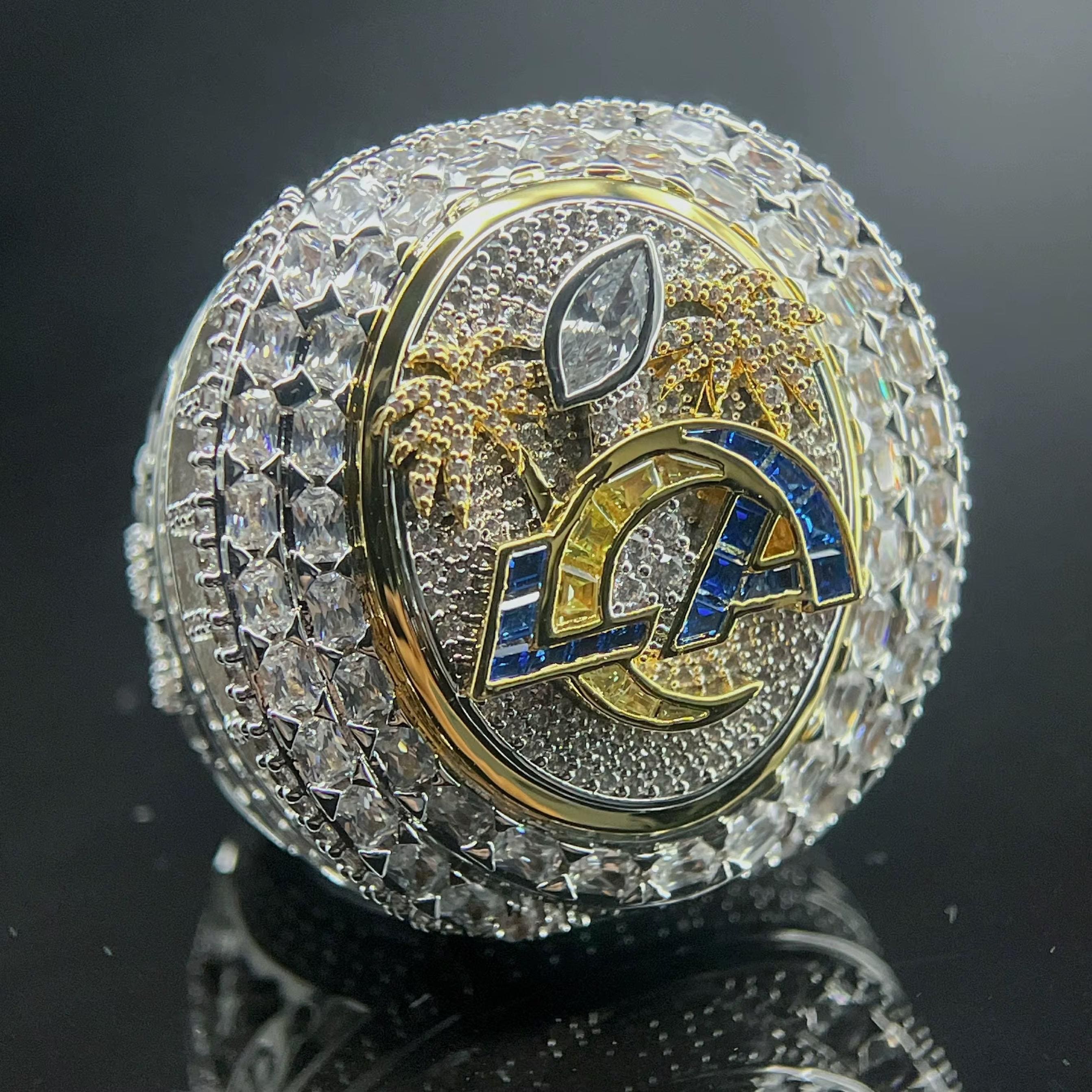 Luxury ring with diamond-studded band and emblem on a reflective surface