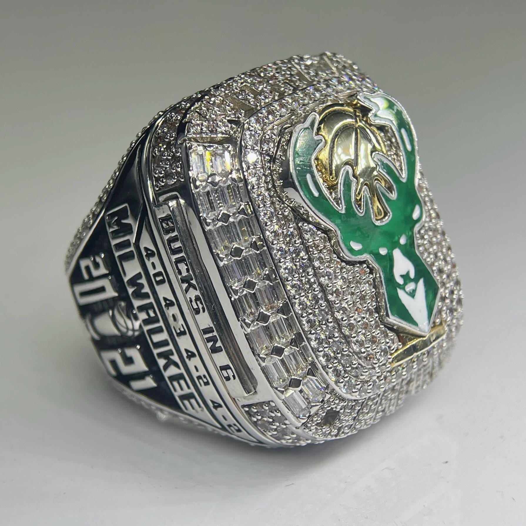 Silver championship ring with green and gold emblem on a gray background