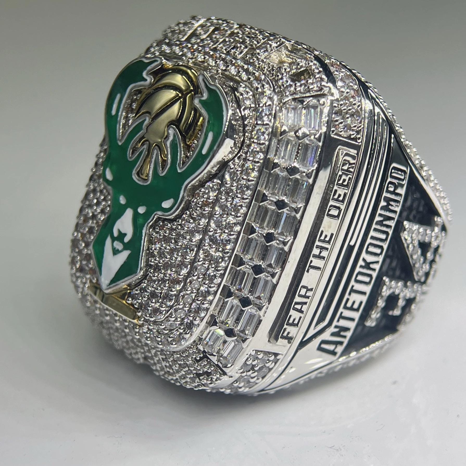 Silver championship ring with green and gold emblem on a gray background