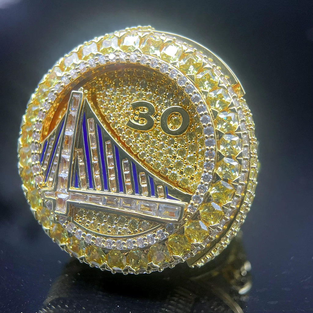 Gold ring with '30' and bridge design on a dark background