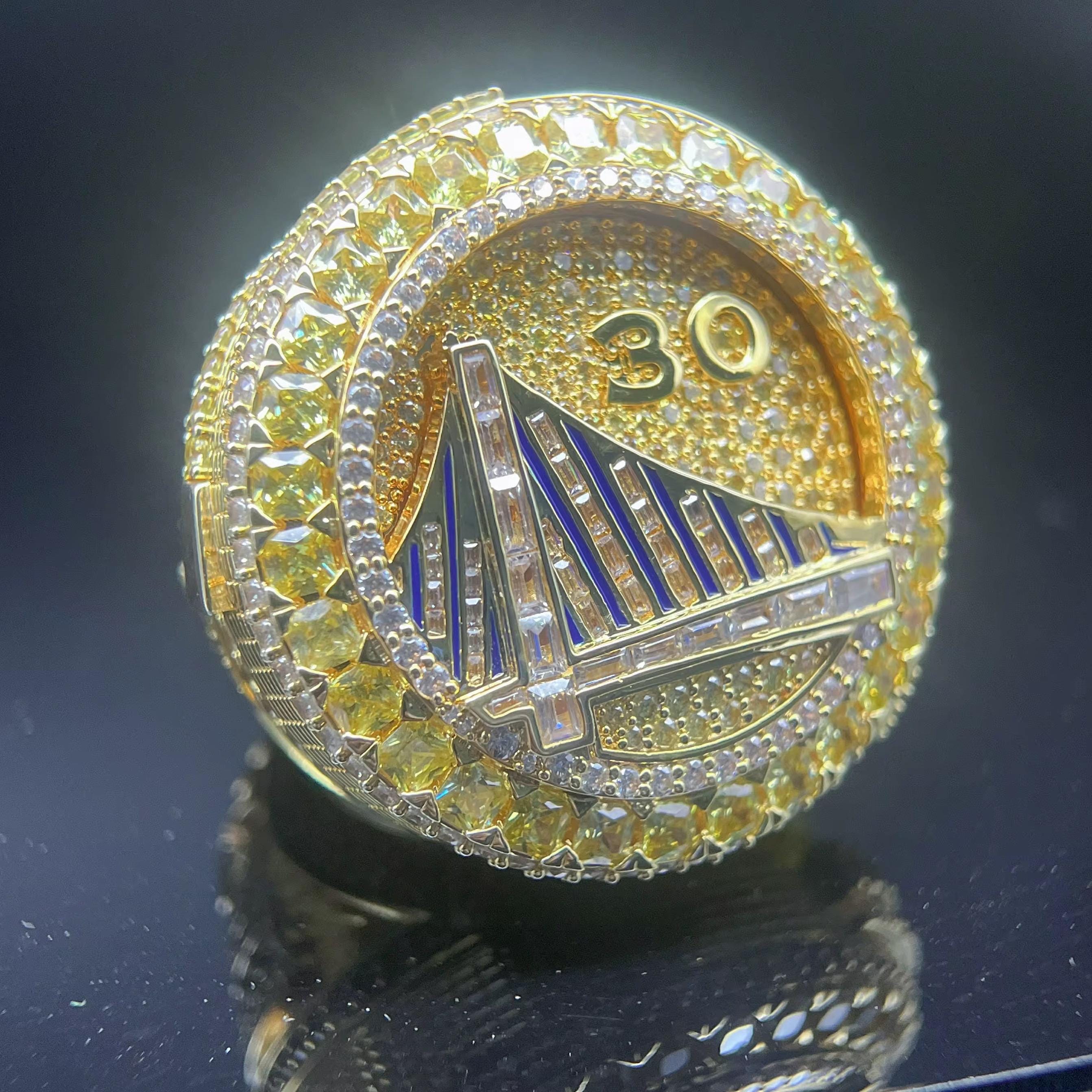 Gold and diamond-encrusted ring with a bridge design on a dark background