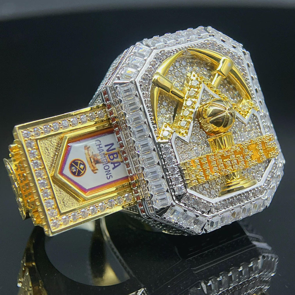 Gold and silver NBA championship ring with trophy design on a black background