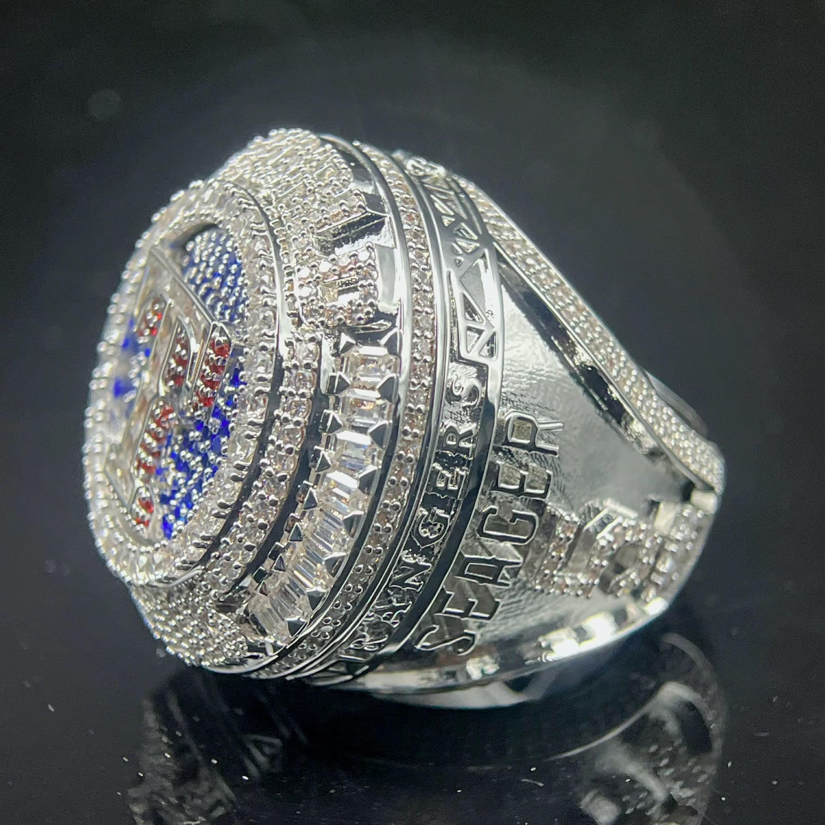 Silver ring with detailed design on a reflective black surface