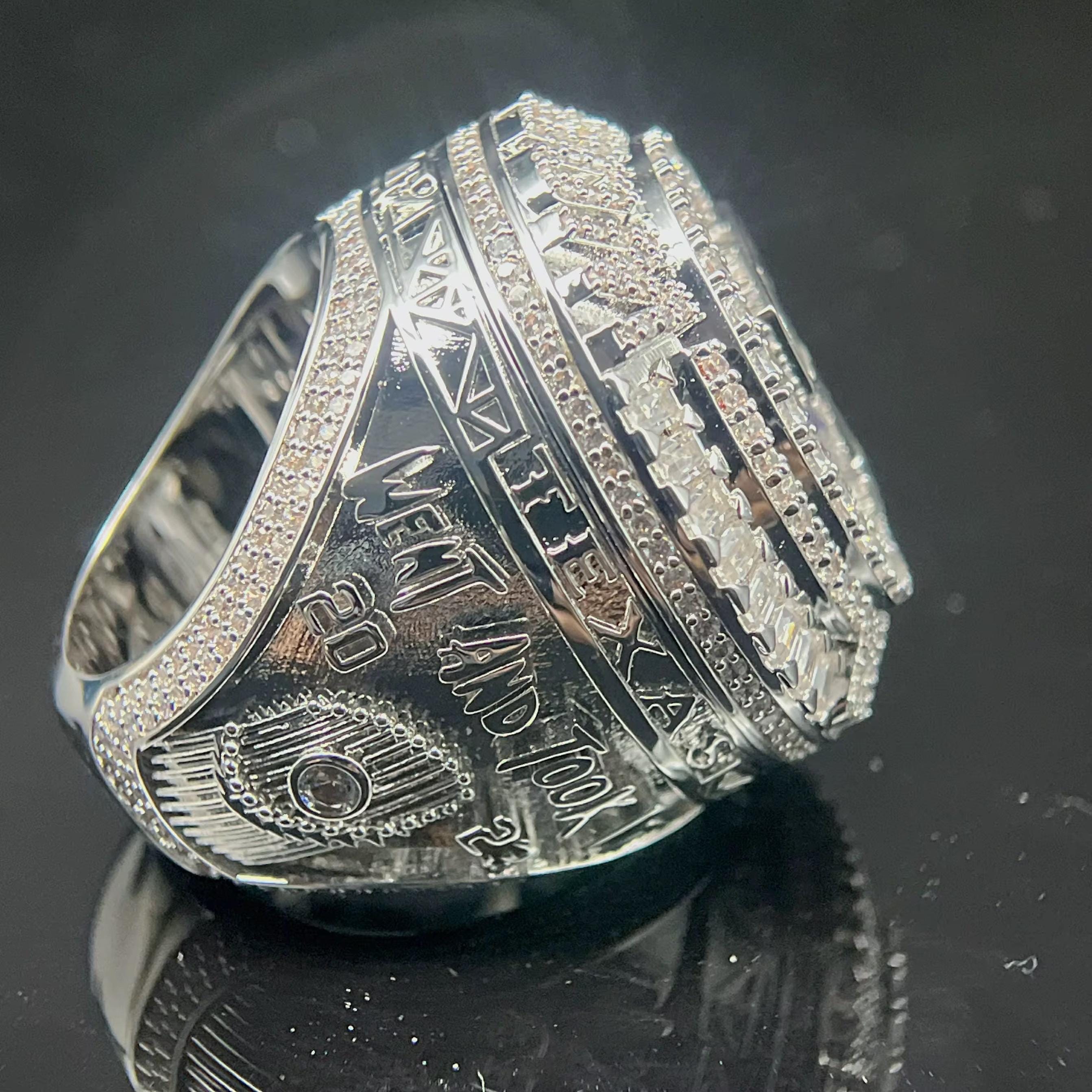 Silver ring with intricate design on a reflective black surface