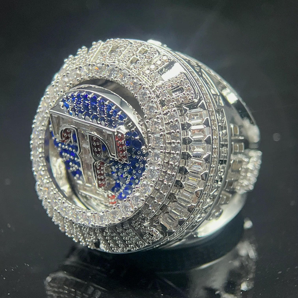 Silver ring with blue and red accents on a reflective black surface