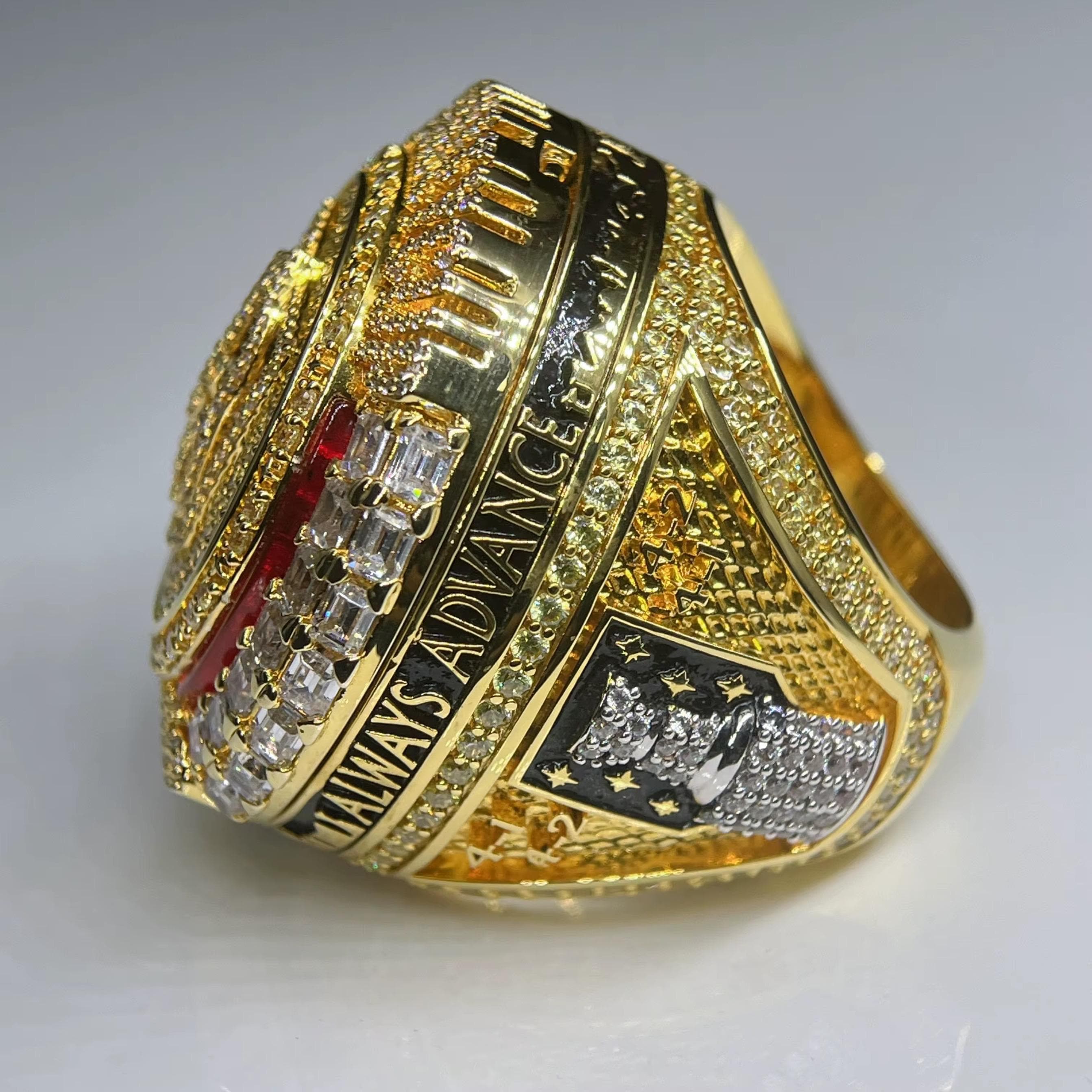 Gold championship ring with engraved text and diamonds on a white background