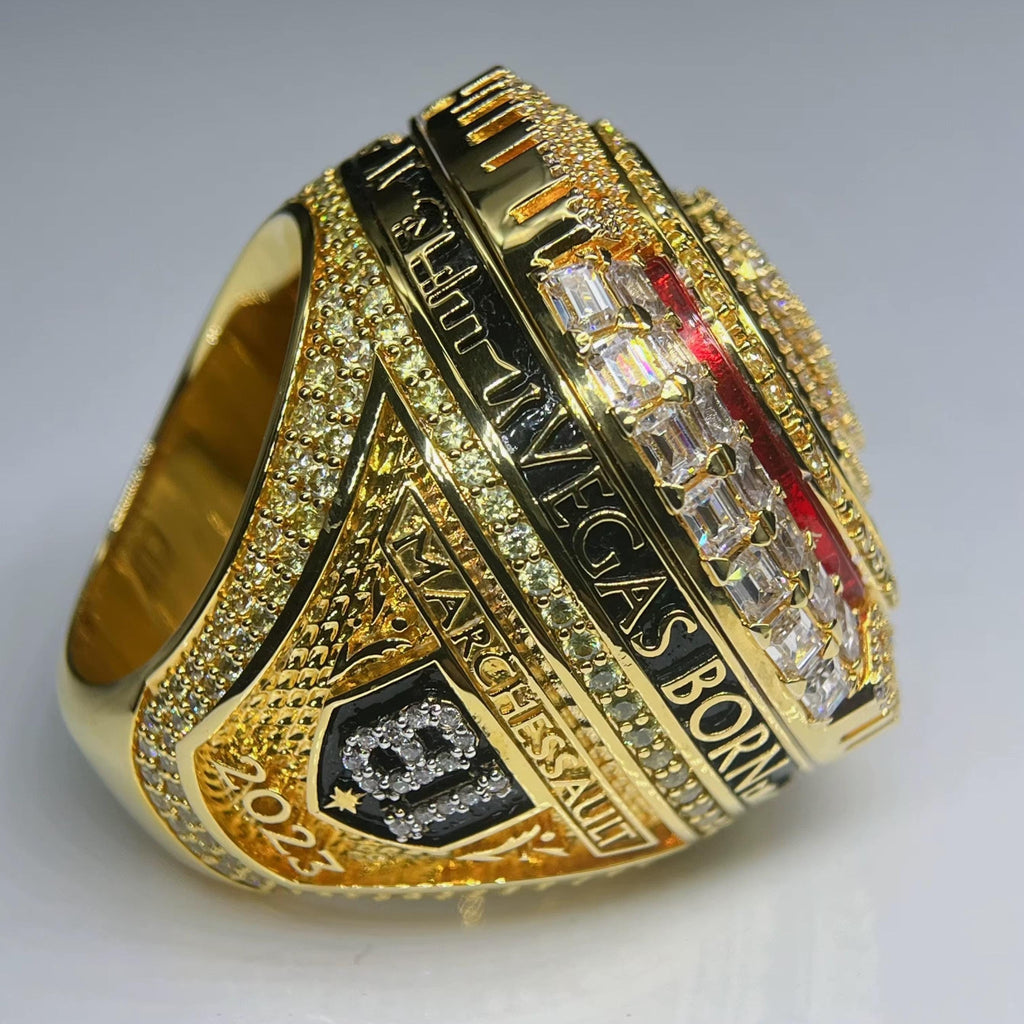 Gold ring with engraved text and gemstones on a gray background