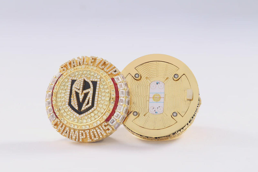 Gold championship ring with a logo on a white background