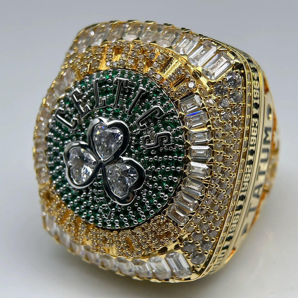 Gold championship ring with green and silver emblem on a white background
