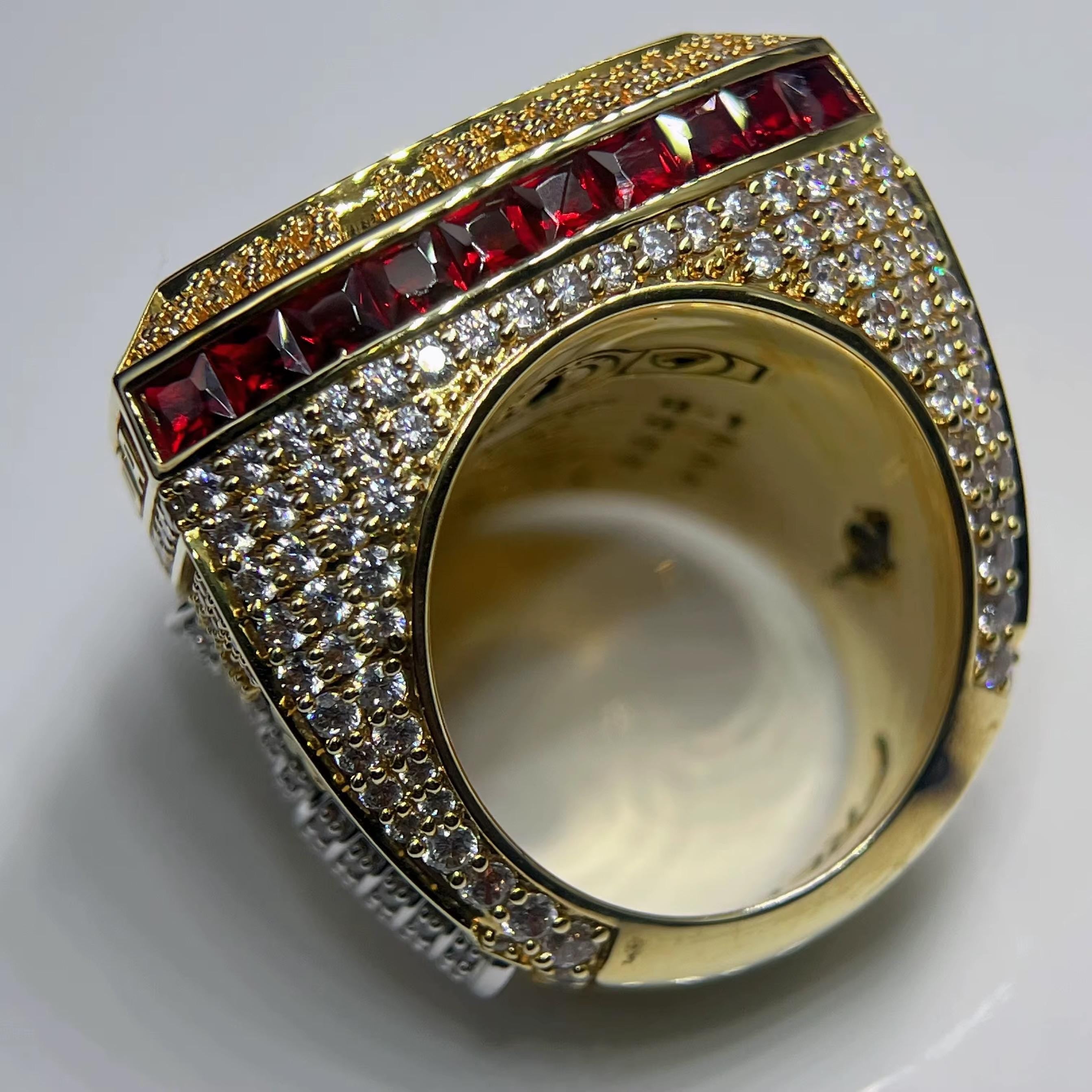 Gold ring with red gemstones and diamonds on a white background