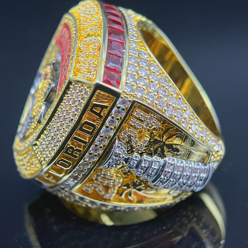 Gold championship ring with diamond accents on a dark background