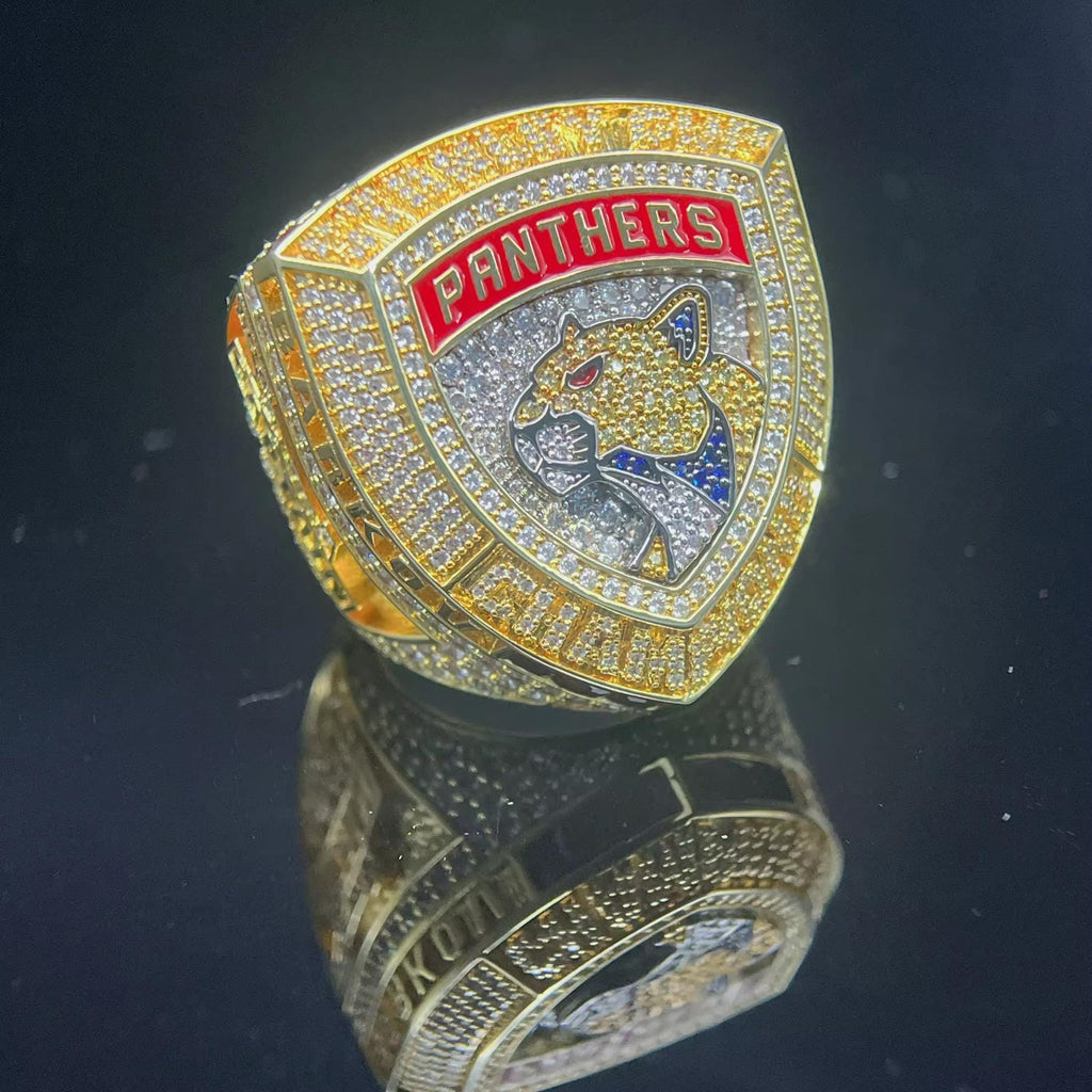 Gold and silver ring with 'Panthers' logo on a reflective surface
