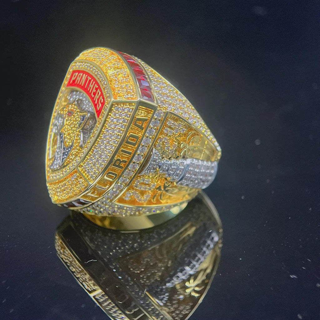 Gold championship ring with 'Panthers' and 'Florida' text on a reflective surface