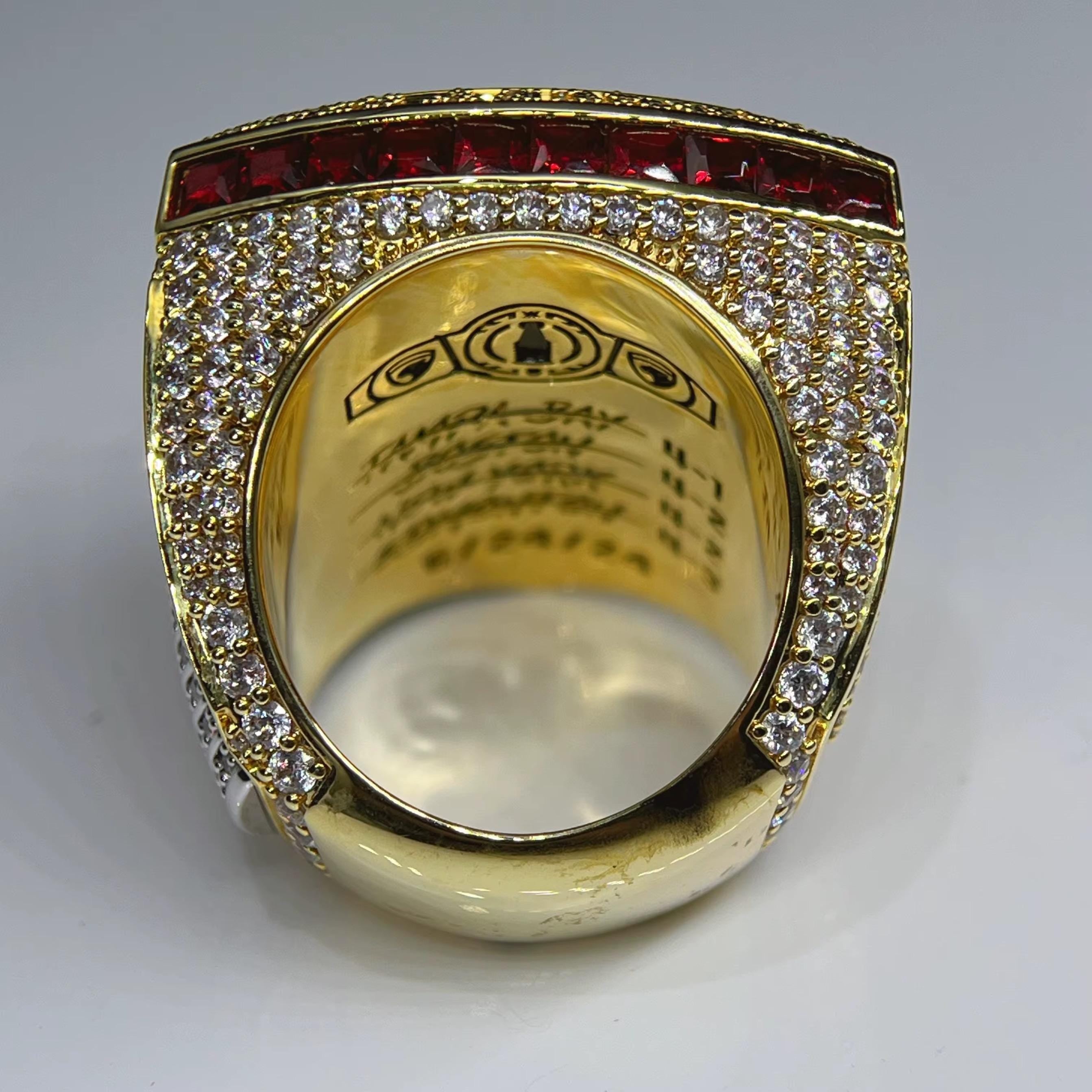 Gold ring with red and white gemstones on a gray background