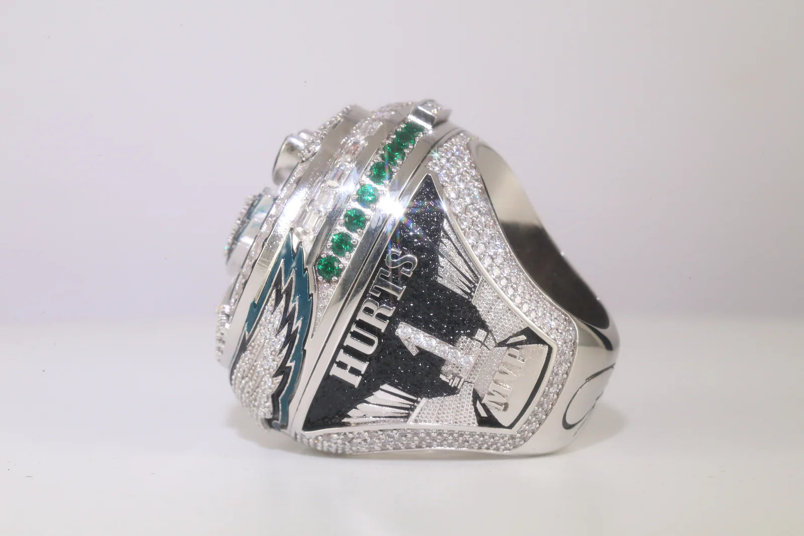 Silver championship ring with emerald stones on a white background