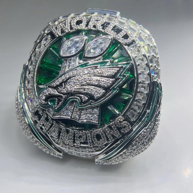 Silver championship ring with green and blue accents on a white background