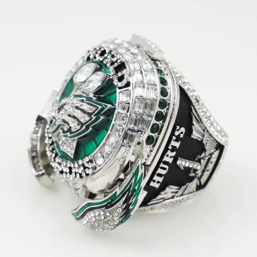 Silver championship ring with green and black details on a white background